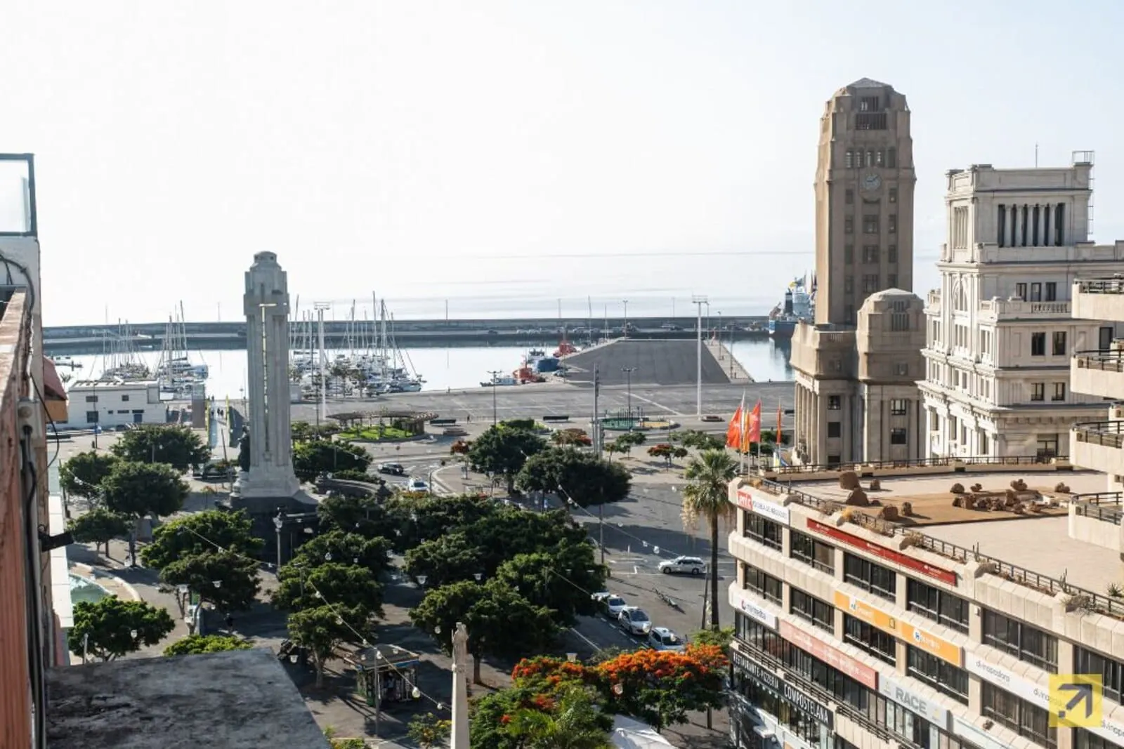 Hotel Adonis Plaza: A marina with boats, a tall monument, and buildings with classical architecture