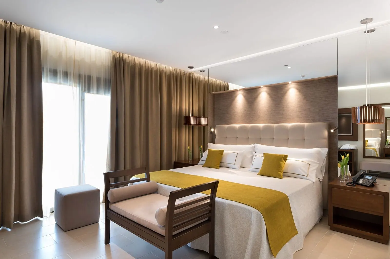 GF Victoria: A modern hotel room with a large bed, a wooden chair, a bedside table with a phone