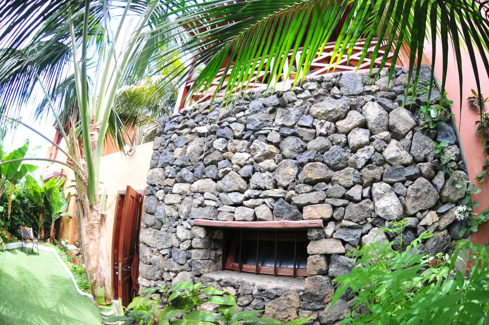 Hotel Emblemático San Marcos: A stone wall with a window, surrounded by lush greenery and a wooden fence