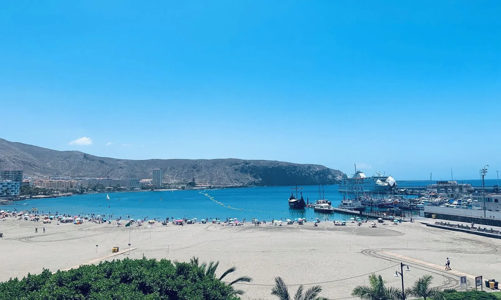 Hotel Reverón Plaza: A coastal beach with a marina, sandy shore, and mountainous backdrop