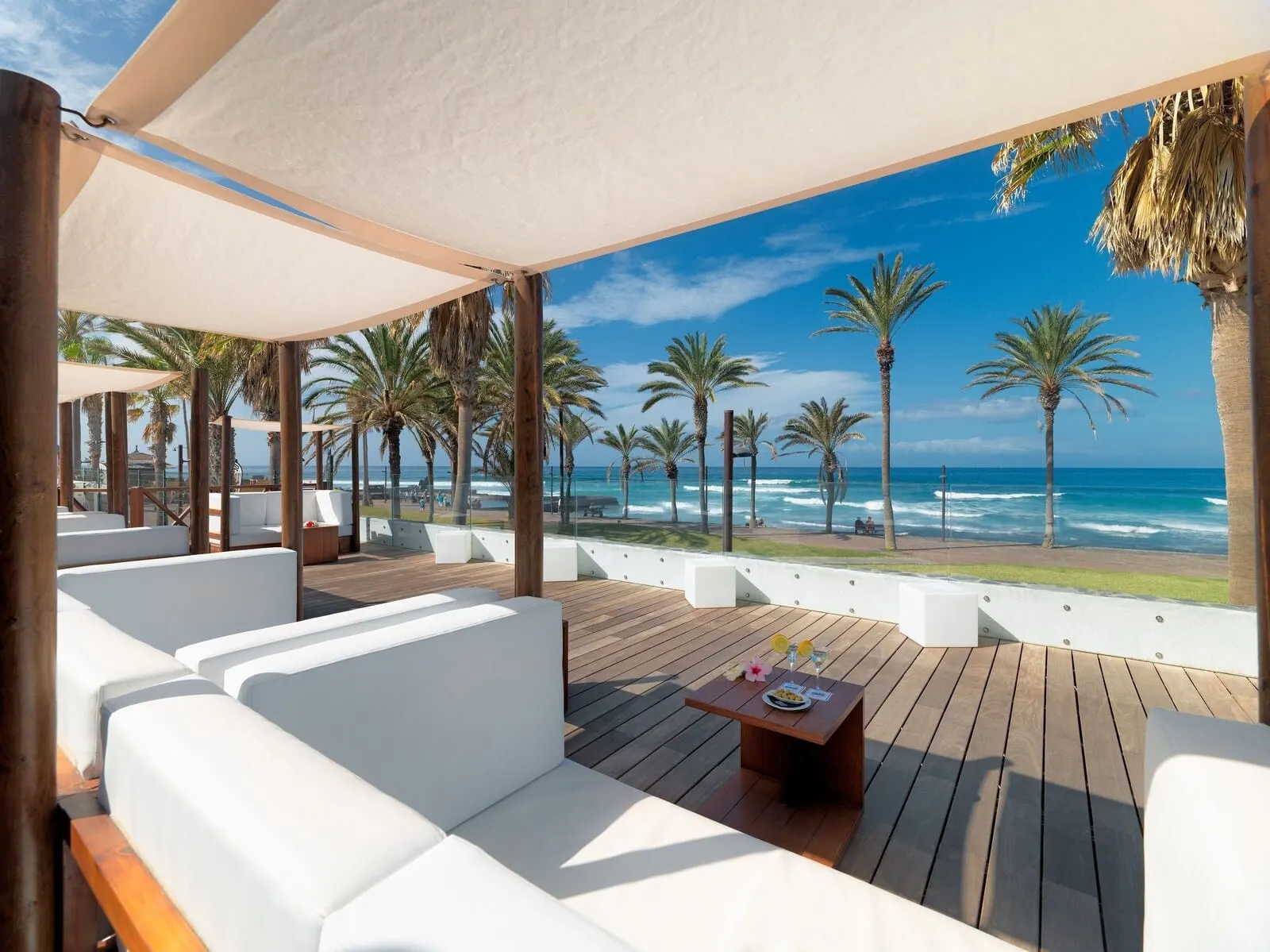 H10 Conquistador: A covered outdoor seating area with white sofas and a wooden table