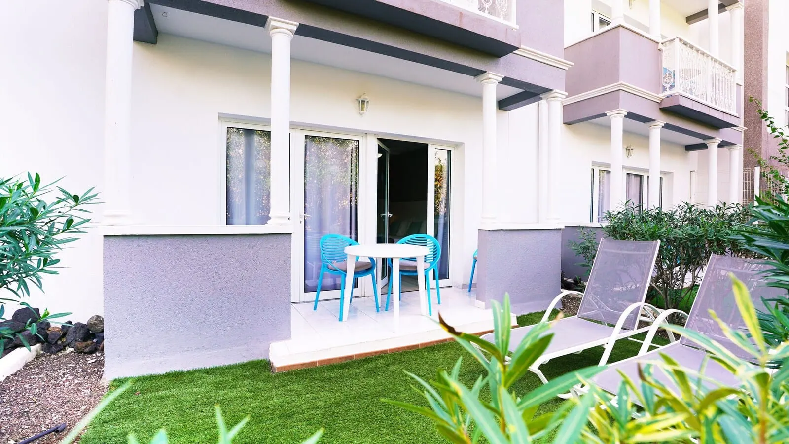 Coral Compostela Beach Golf: A courtyard with a white table and blue chairs, surrounded by greenery and a small lawn