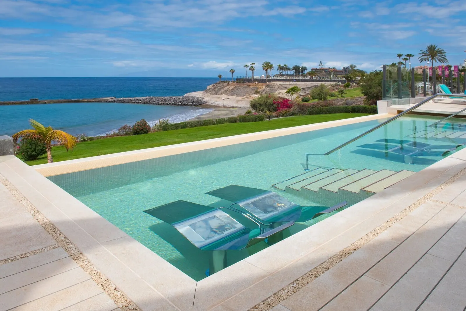 JOIA Salomé by Iberostar: A pool with clear water, lounge chairs, and a view of the ocean and beach
