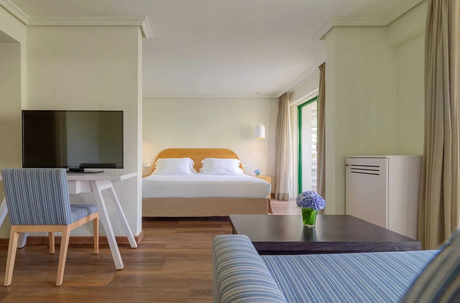 H10 Tenerife Playa: A hotel room with a bed, a TV, a desk, and a sofa