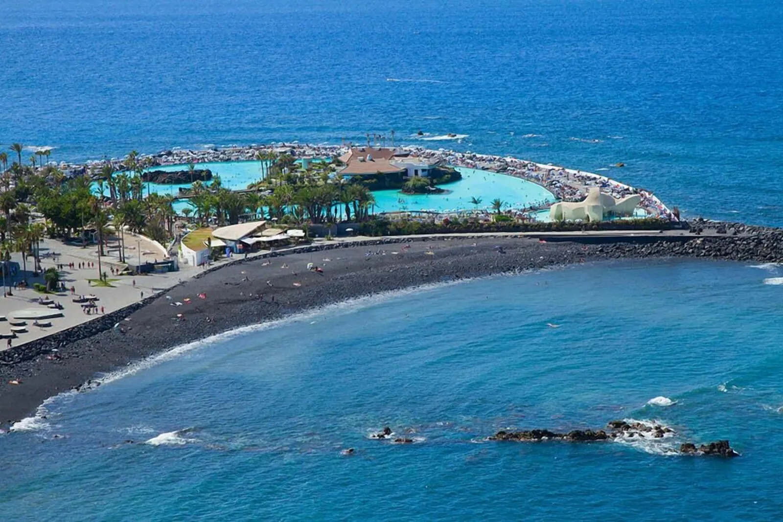 Meliá Costa Atlantis Tenerife: A coastal resort with a beach, a pool area, and a rocky shoreline