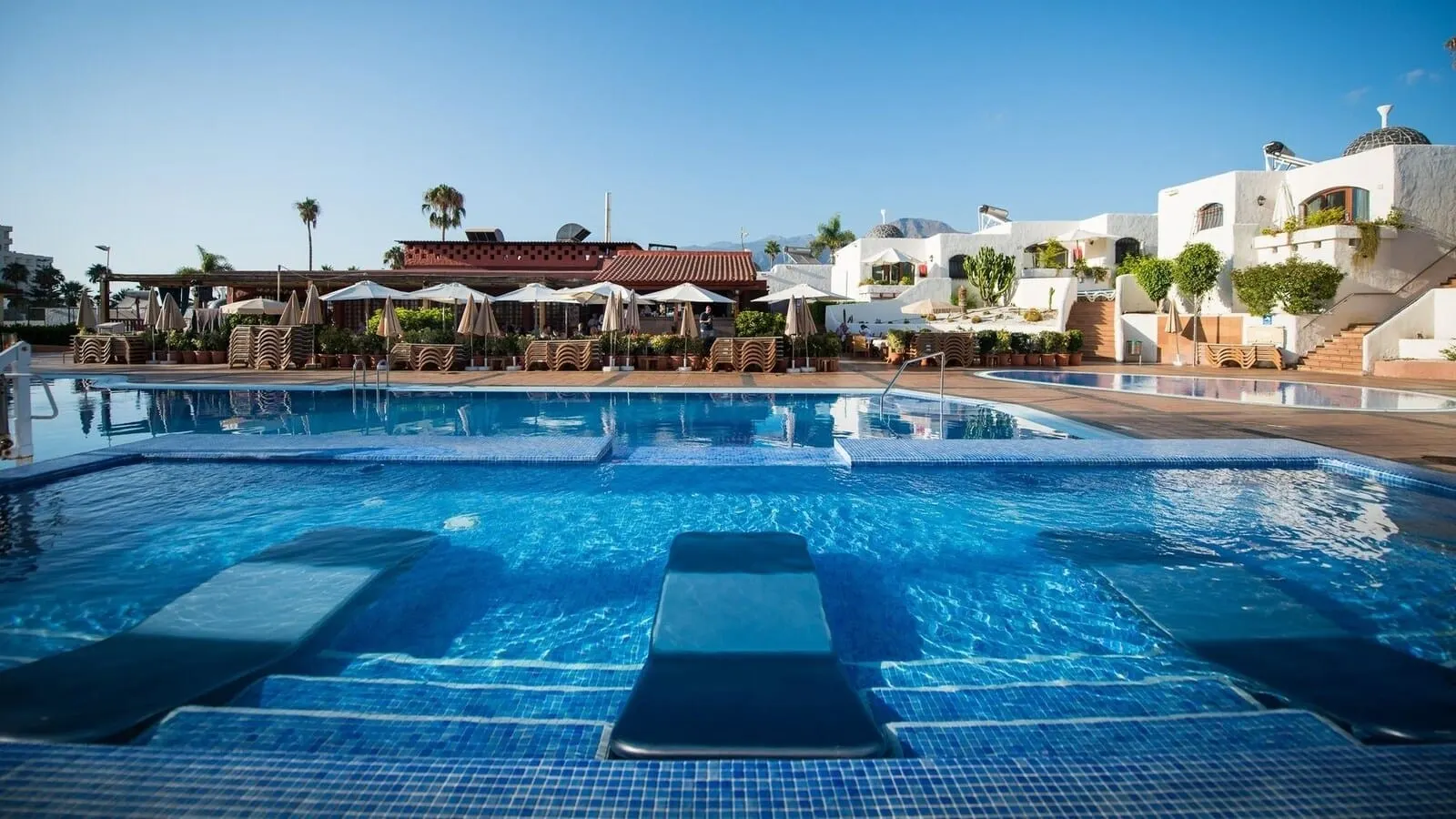 HD Parque Cristóbal Tenerife: A swimming pool with lounge chairs and umbrellas