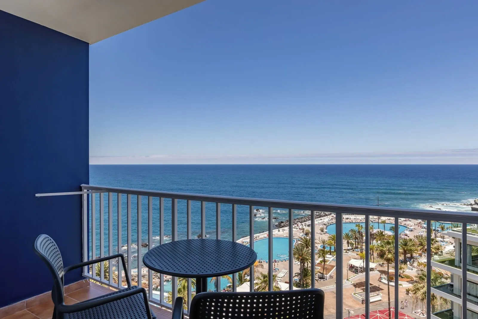 Catalonia Las Vegas: A balcony with two chairs and a table, overlooking a beach with a pool and resort area