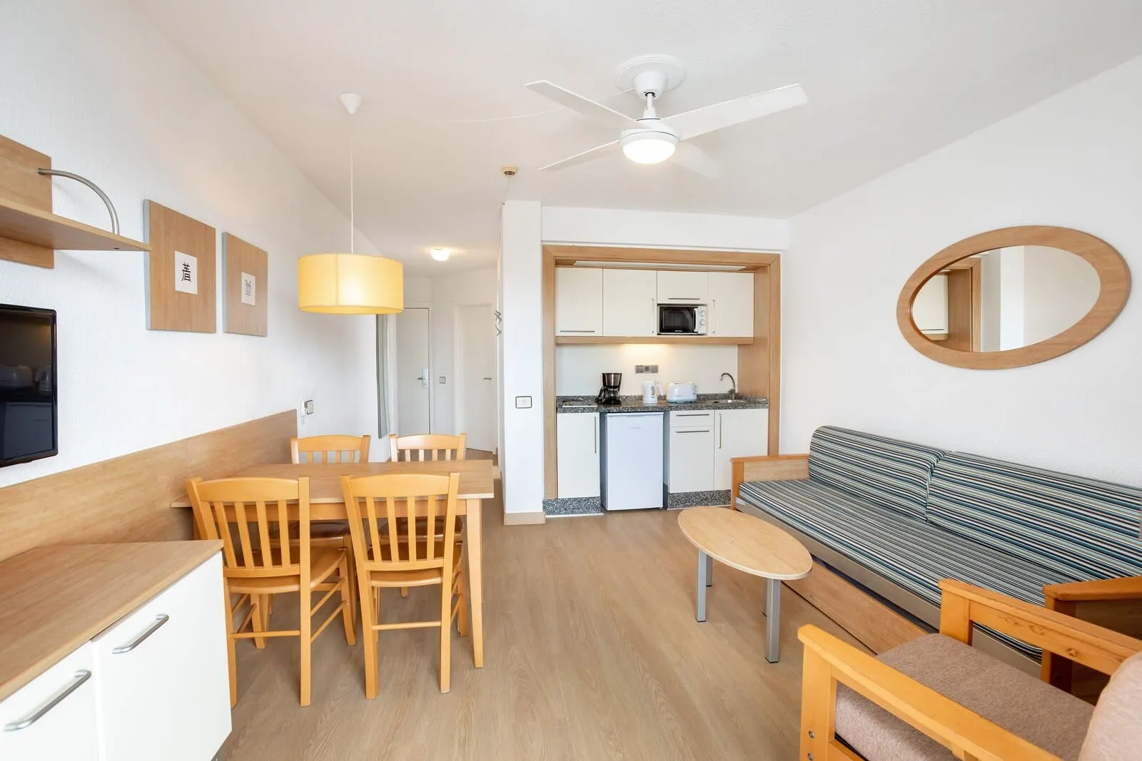 Apartamentos Aguamar: A compact living space with a dining area, kitchenette, and seating area