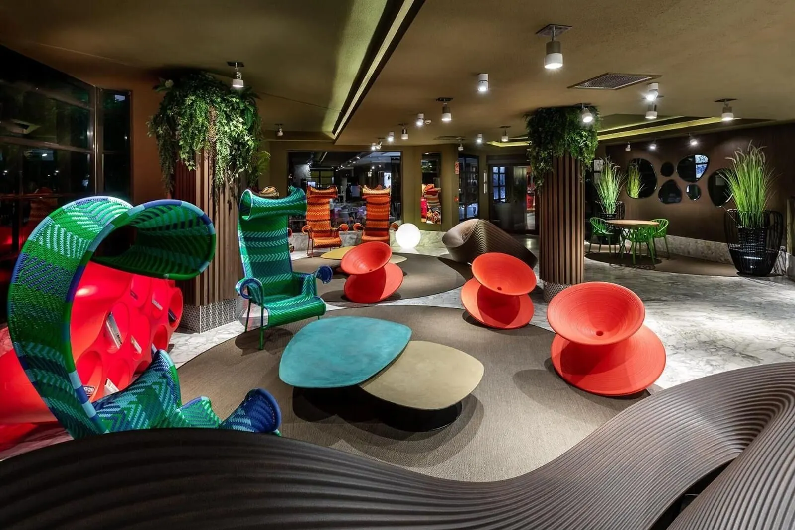 Apartamentos Aguamar: A modern lounge area with colorful seating, green plants, and a well-lit ceiling