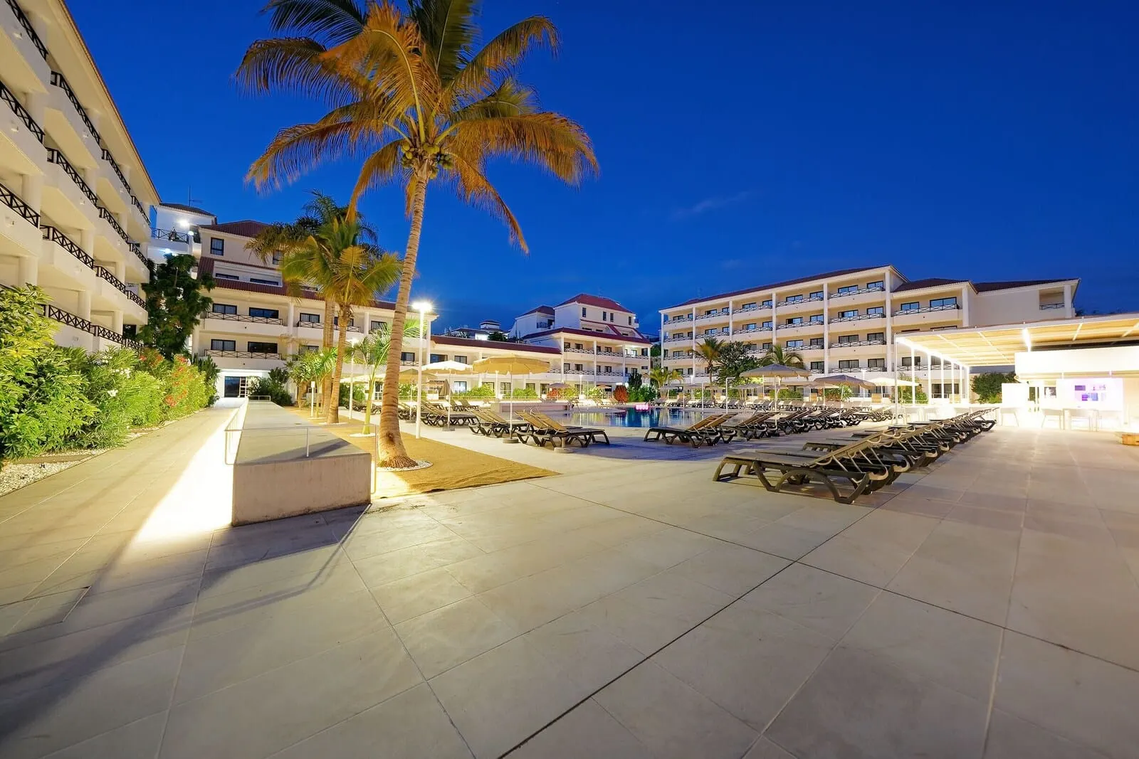 Hotel Parque La Paz: A hotel courtyard with a swimming pool, sun loungers, and palm trees