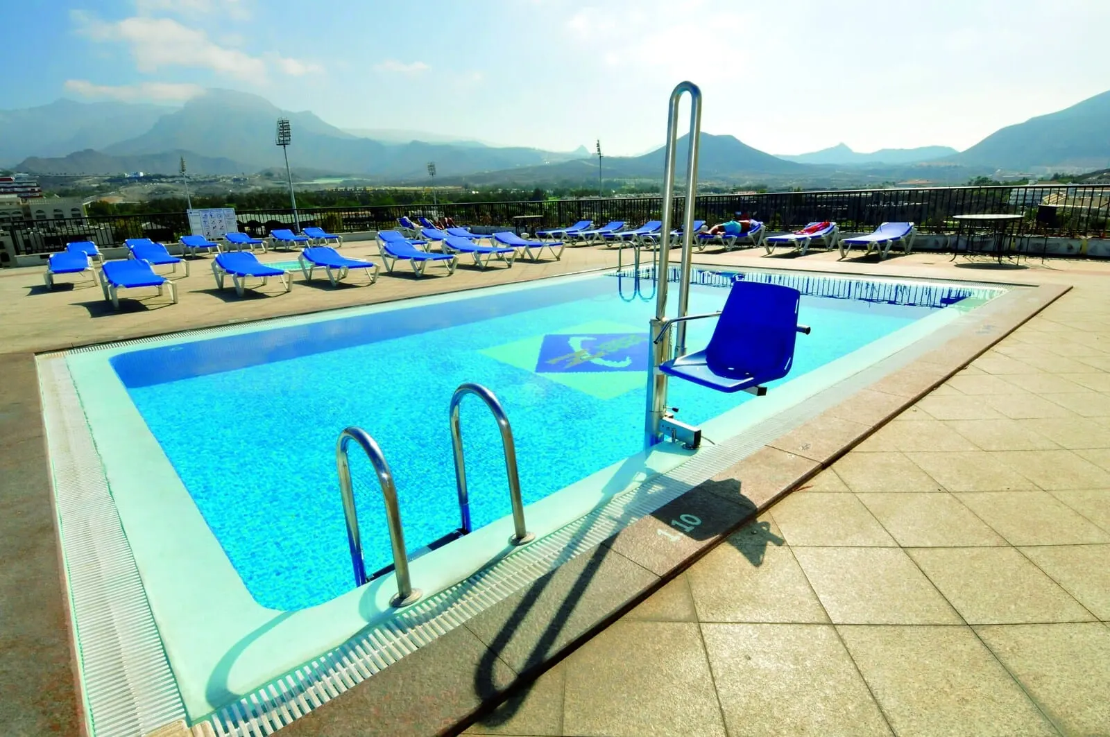 Hotel Zentral Center: A rooftop swimming pool with blue lounge chairs and a view of mountains