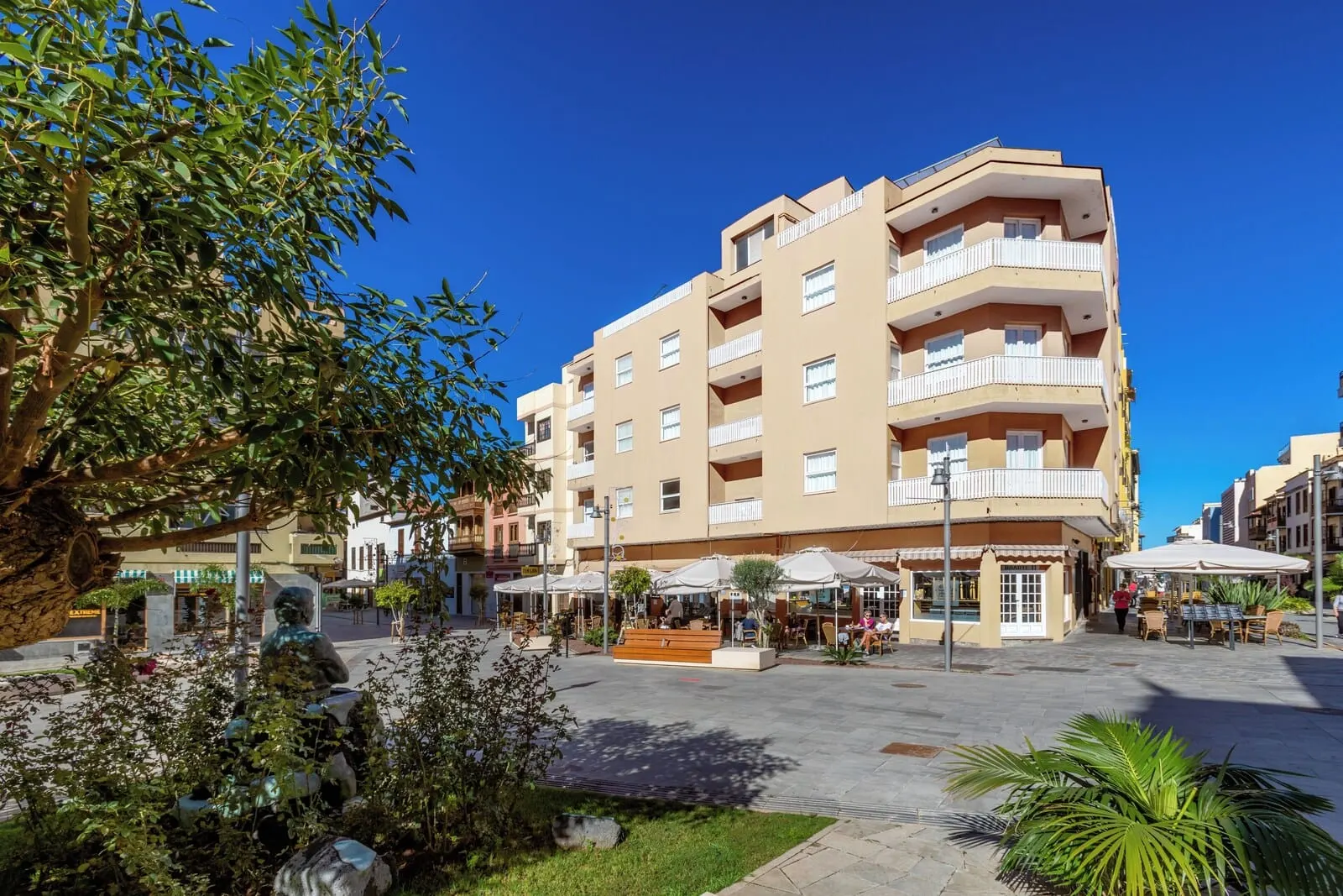 Hotel Boutique HC Maga: A multi-story building with balconies, outdoor seating, and a central courtyard