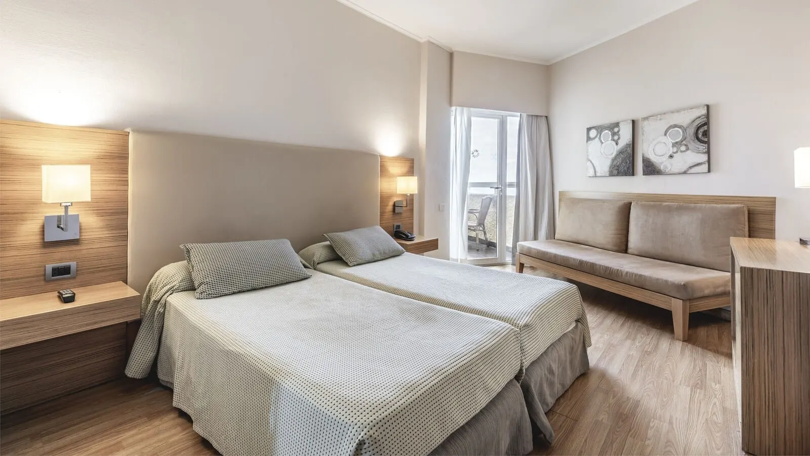 Be Live Adults Only Tenerife: A modern hotel room with a double bed, a sofa, a desk, and a balcony with a view