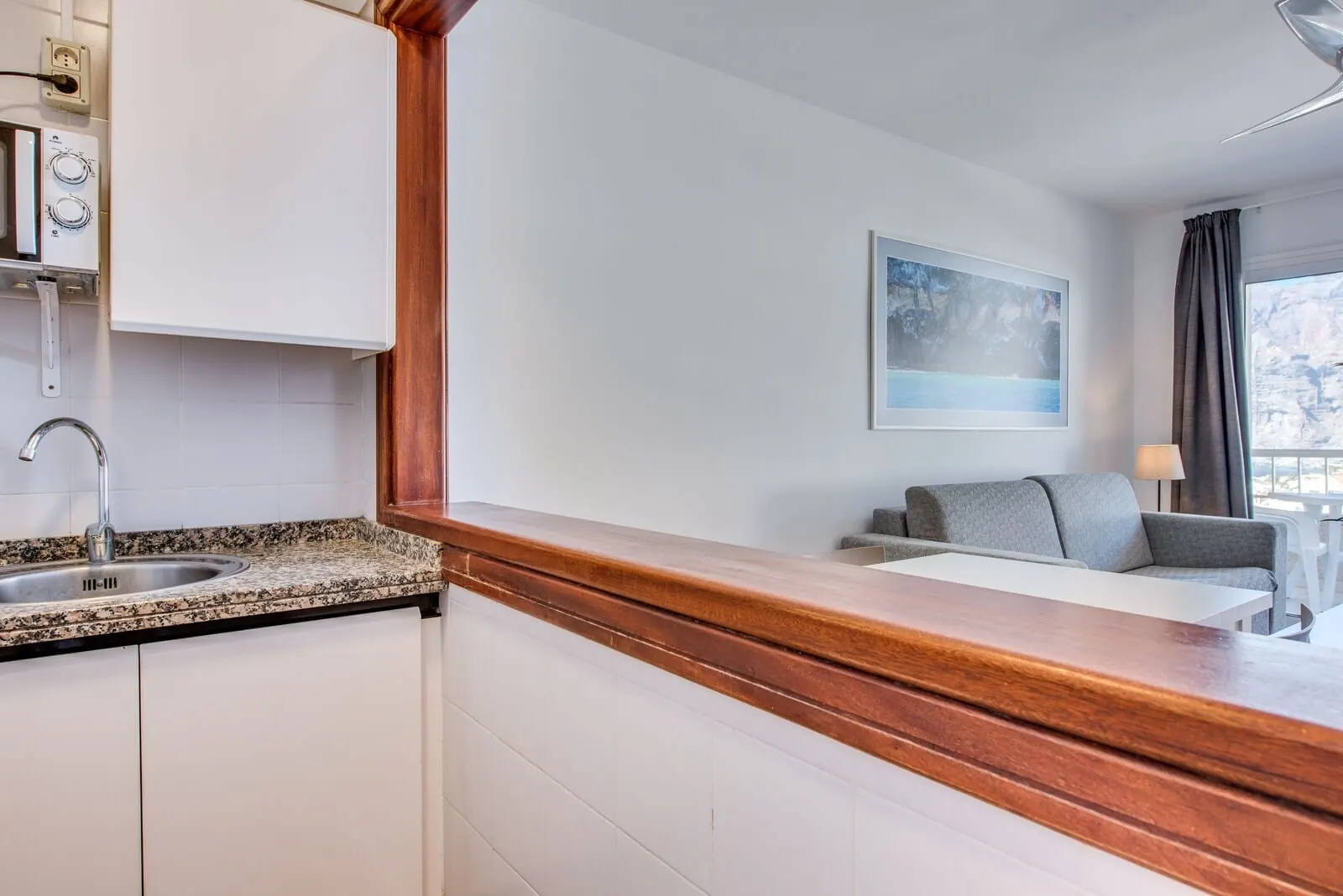 Vigilia Park: A kitchen with a granite countertop, white cabinets, and a wooden backsplash