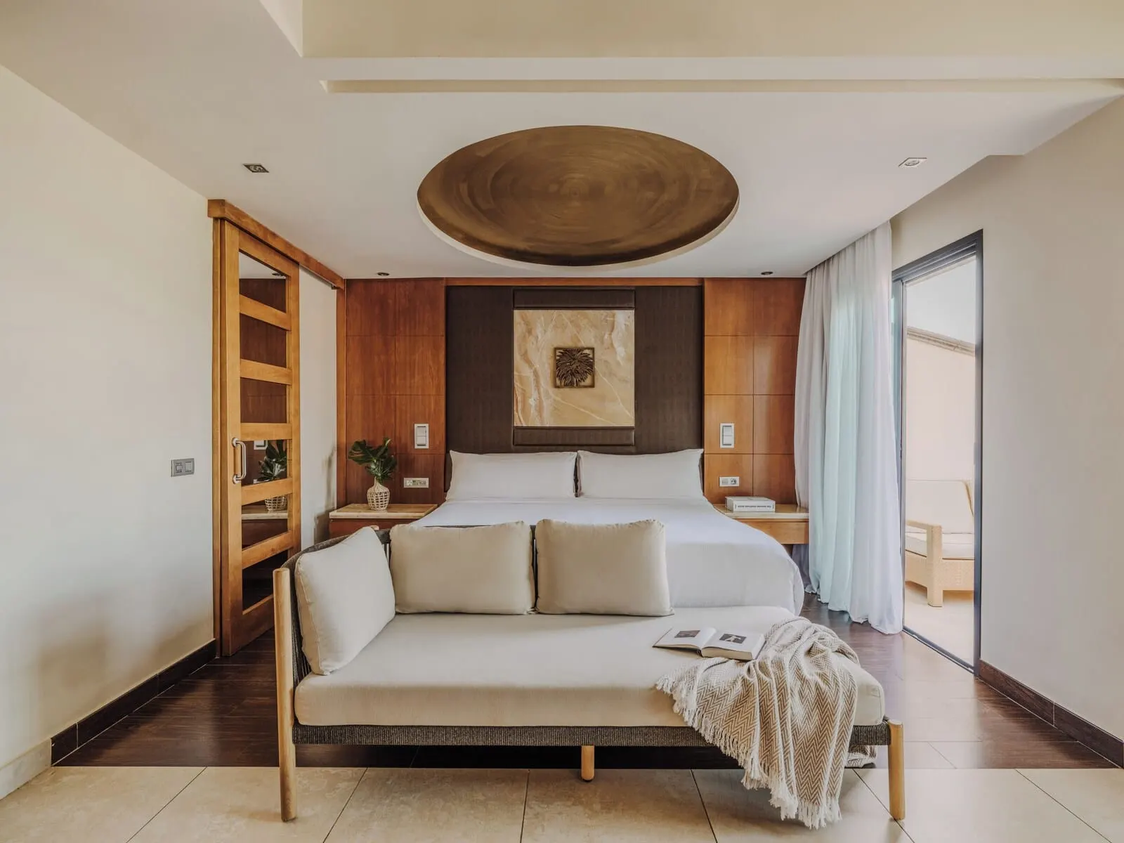 Gran Meliá Palacio de Isora: A modern bedroom with a bed, a sofa, a wooden cabinet