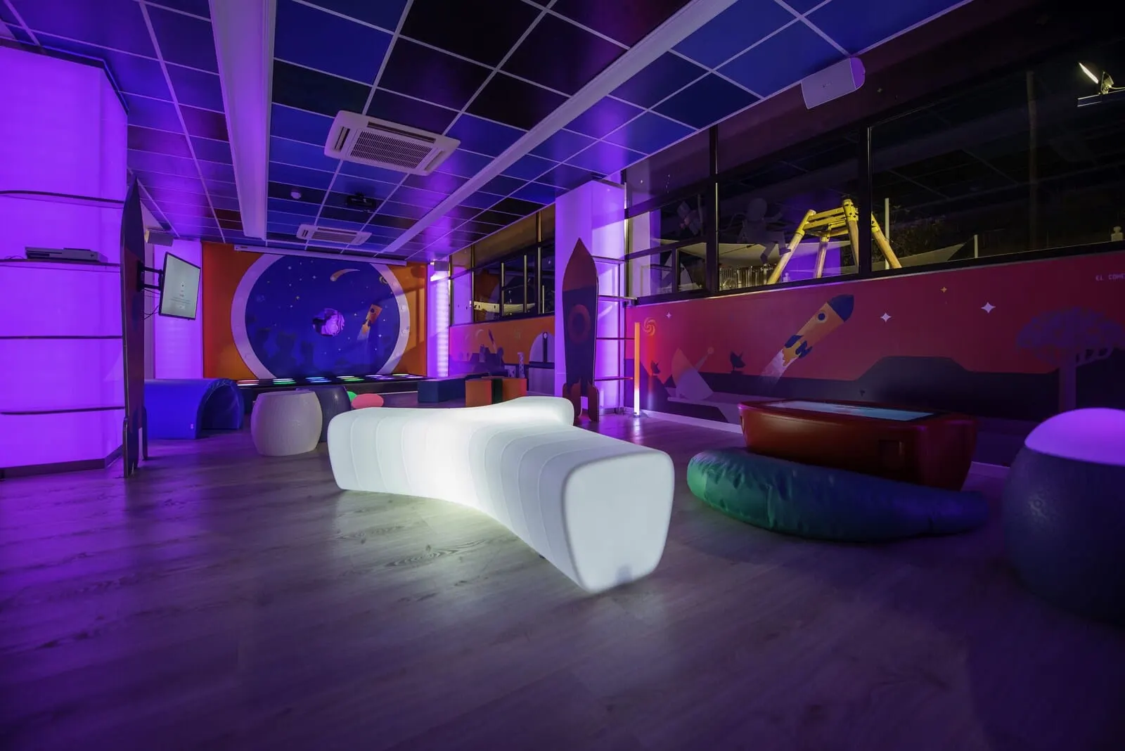 Spring Hotel Bitácora: A modern, brightly lit room with a curved white bench, colorful bean bags