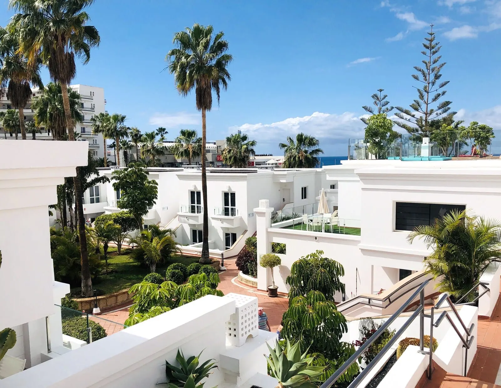 Flamingo Beach Mate: A residential area with white buildings, palm trees, and a clear sky