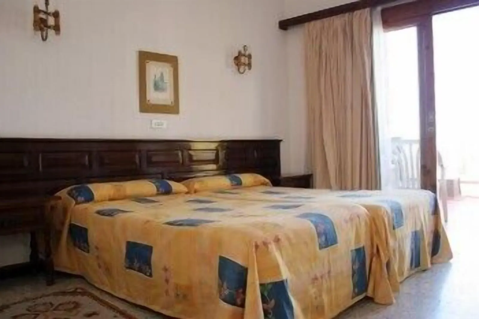 Hotel Tejuma: A bedroom with a large bed, wooden headboard, and a window with curtains