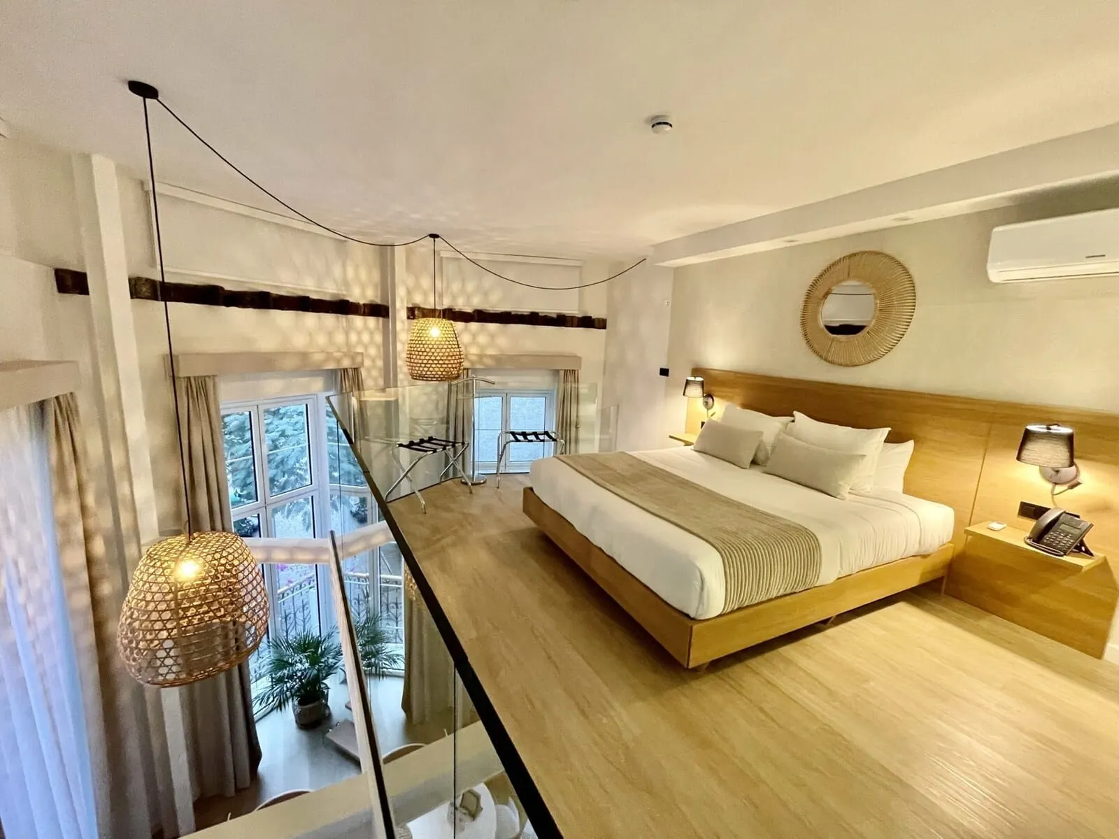 Hi Suites: A modern hotel room with a large bed, a glass partition, a balcony with plants