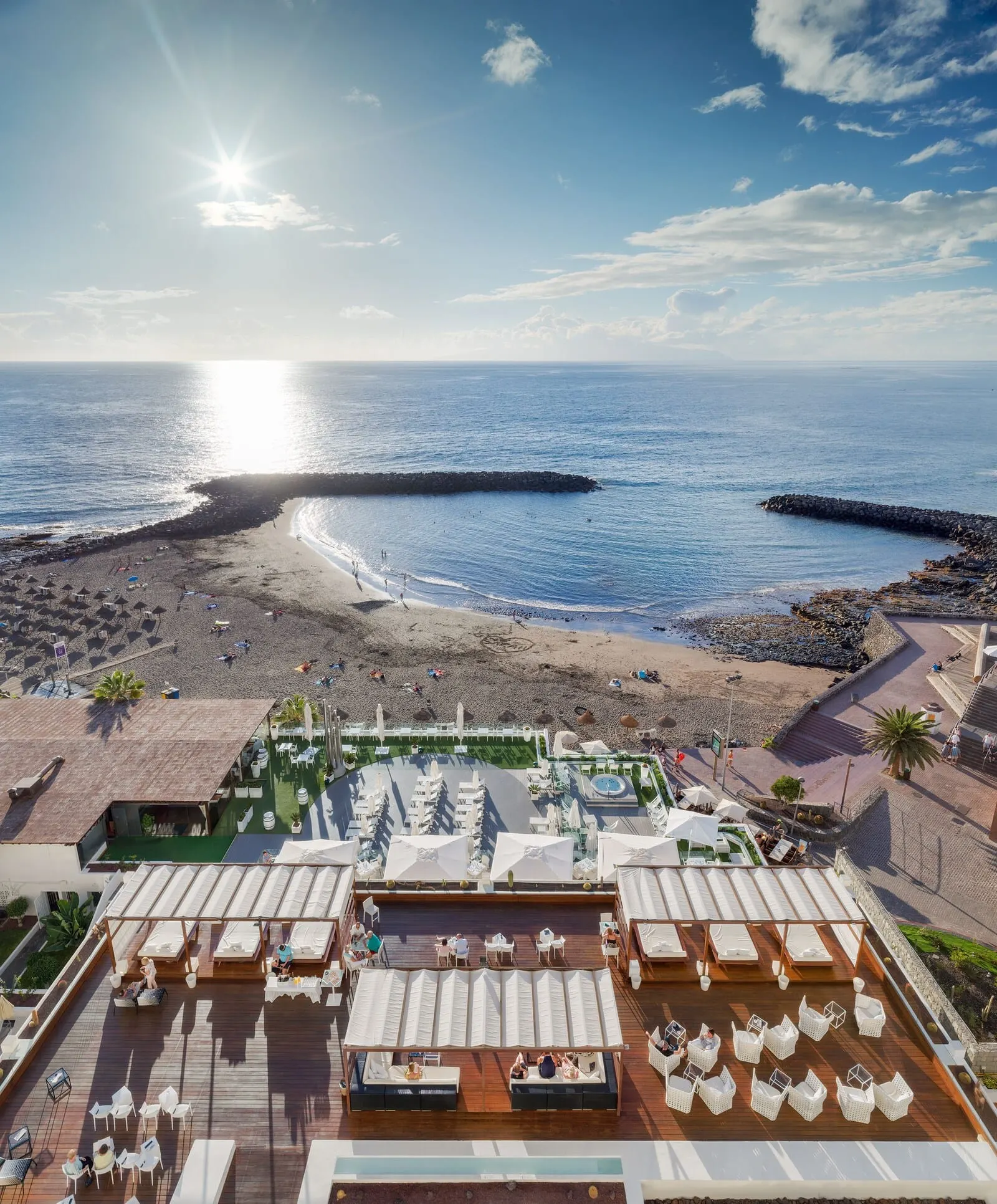 H10 Gran Tinerfe: A rooftop bar with outdoor seating, a pool, and a view of the beach and ocean