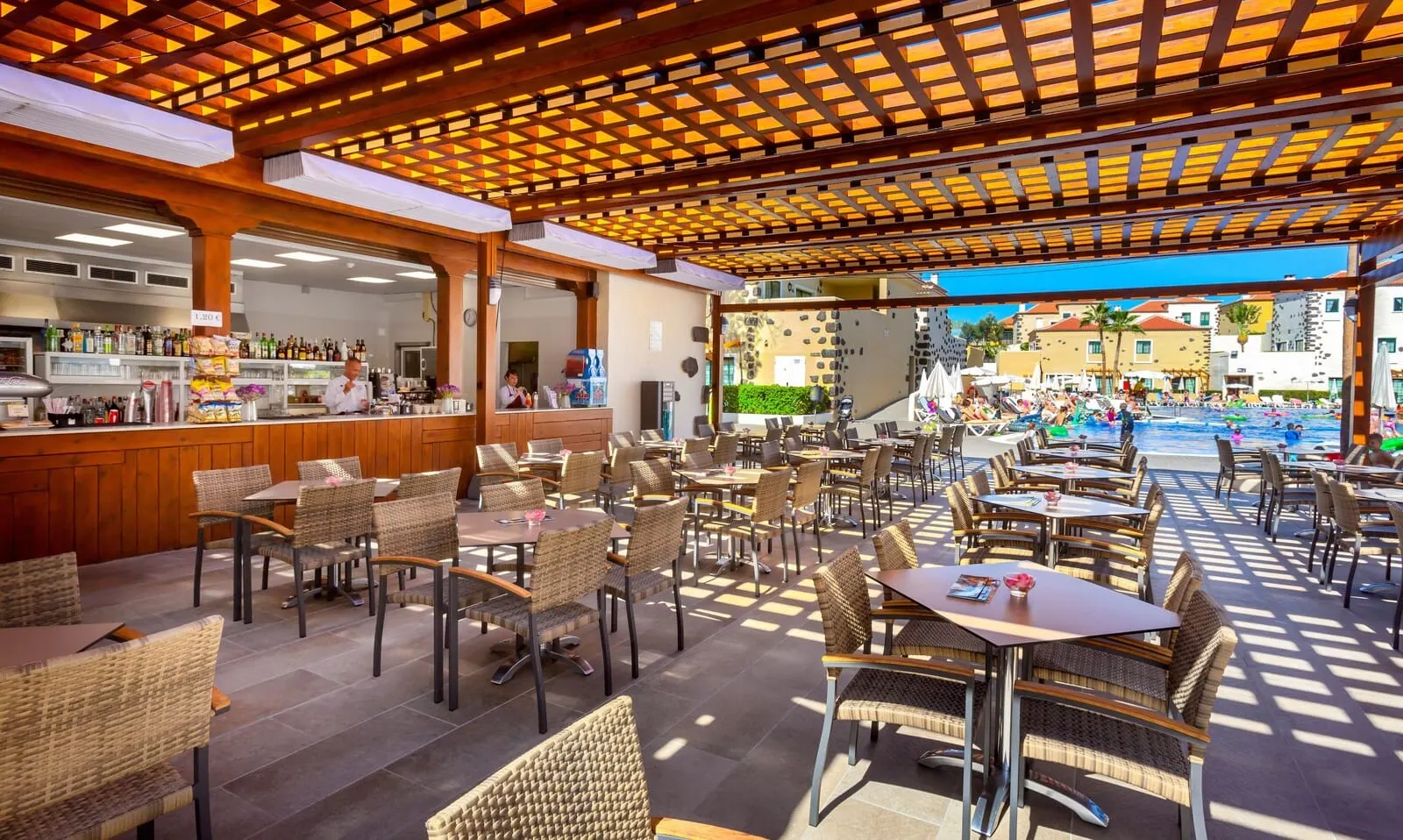 GF Isabel: An outdoor cafe area with wicker furniture and a pool in the background
