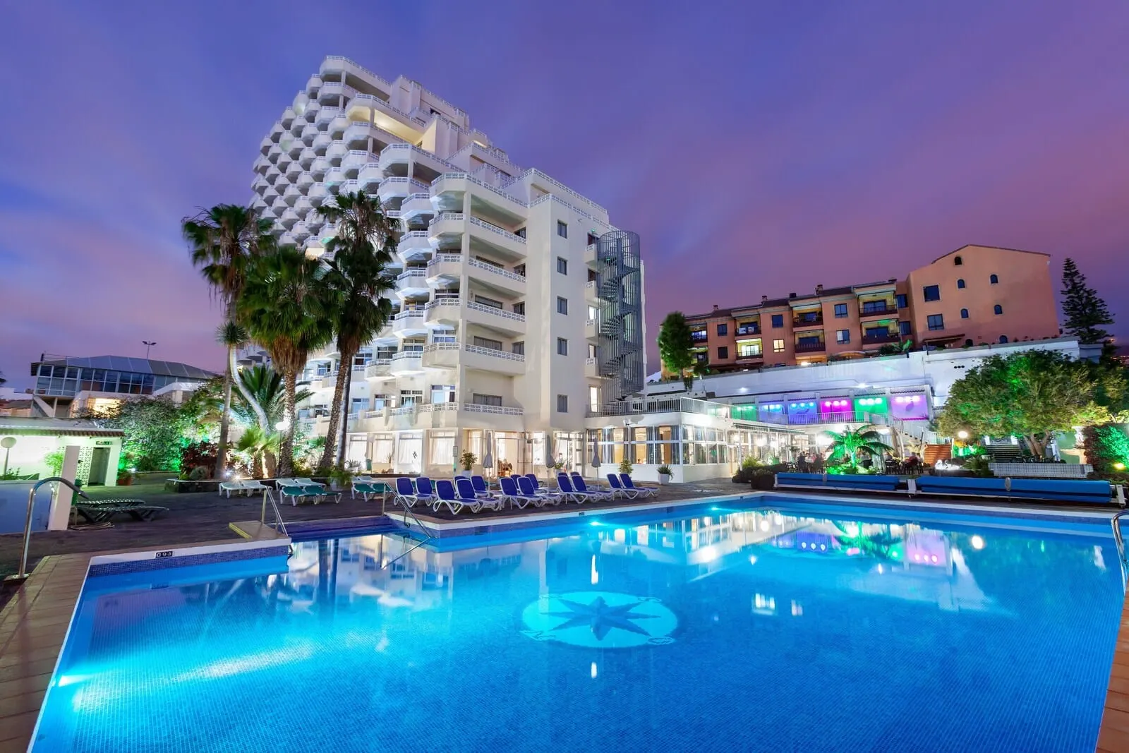Hotel Panorámica Garden: A hotel with a pool, palm trees, and a modern building with balconies