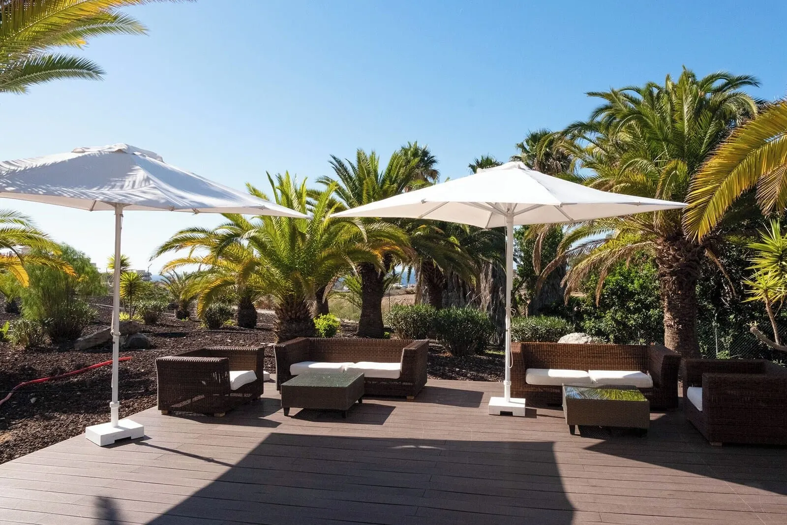 Grand Muthu Golf Plaza Hotel & Spa: A deck with wicker furniture and white umbrellas, surrounded by palm trees