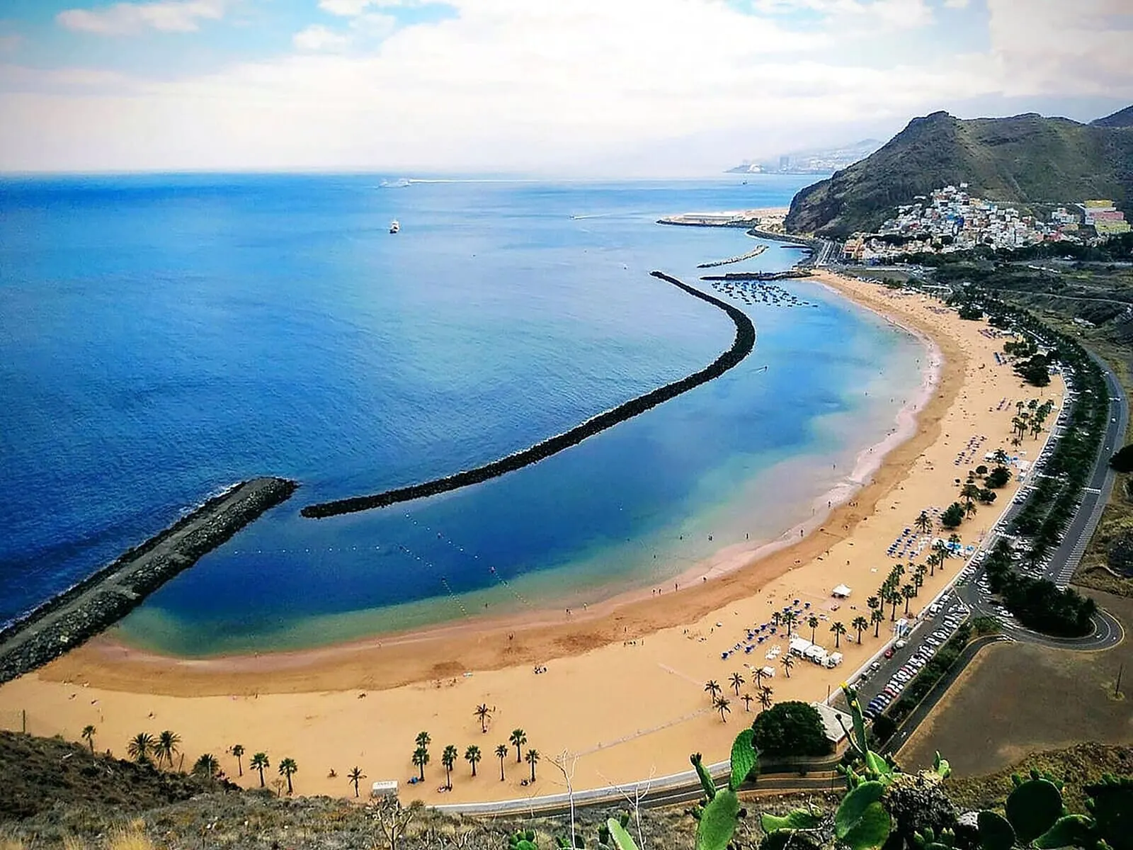 Adonis La Suite: A coastal beach with a curved breakwater, a sandy shore