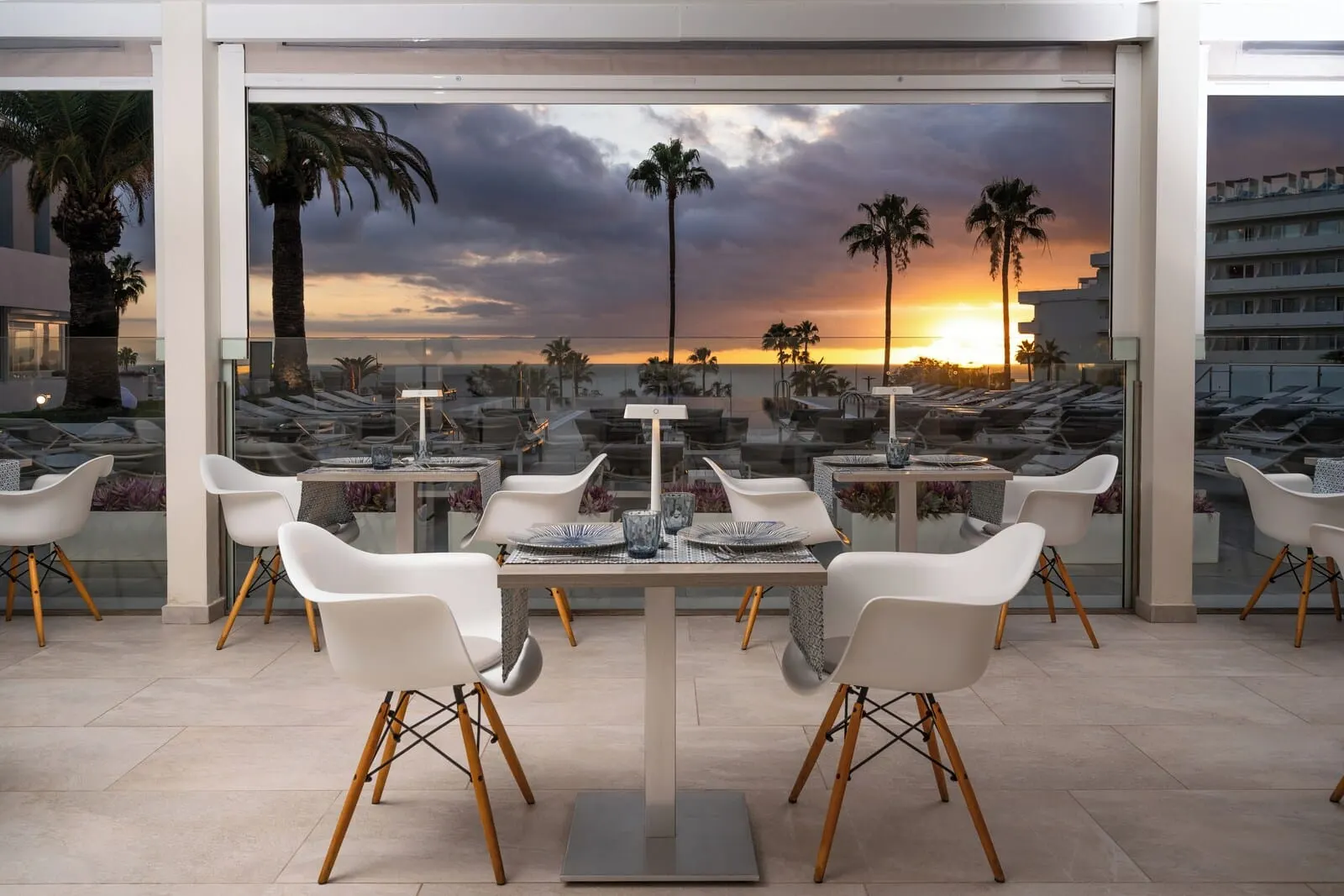 HOVIMA Cool Costa Adeje: A modern outdoor dining area with a glass table and white chairs