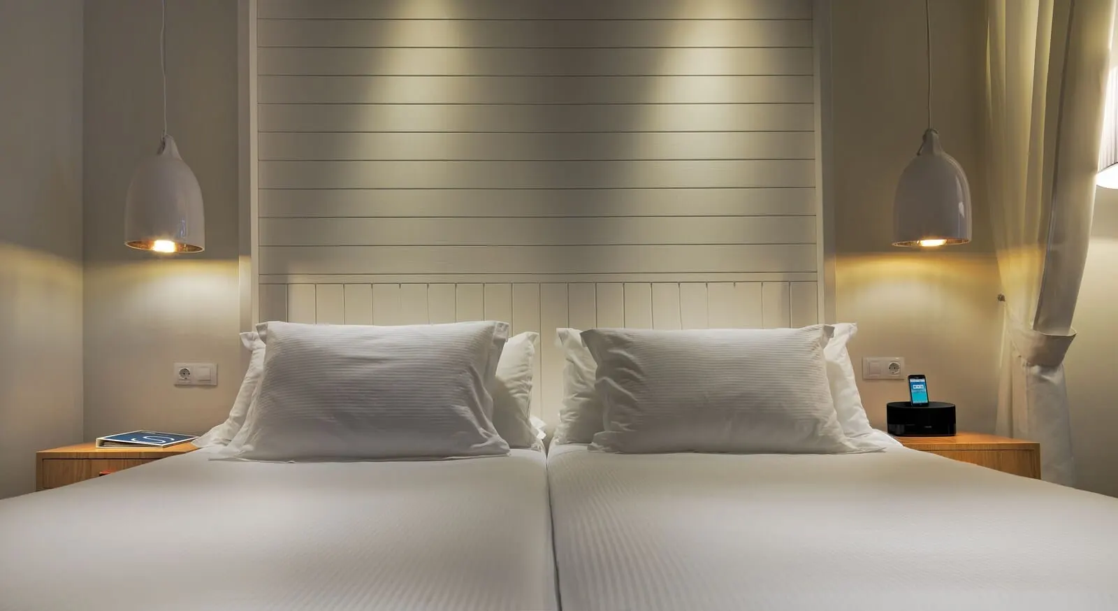 H10 Conquistador: A double bed with white linens, two bedside tables, a wall-mounted light fixture