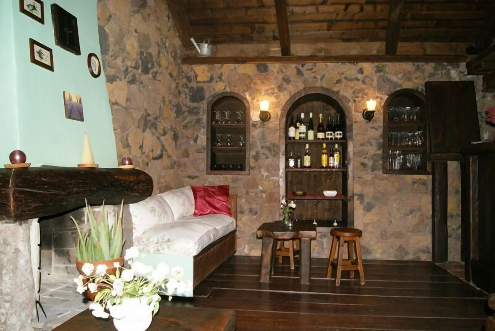 Hotel Rural Caserío Los Partidos: A cozy room with a stone wall, a wooden bench, a sofa, and a small table with stools