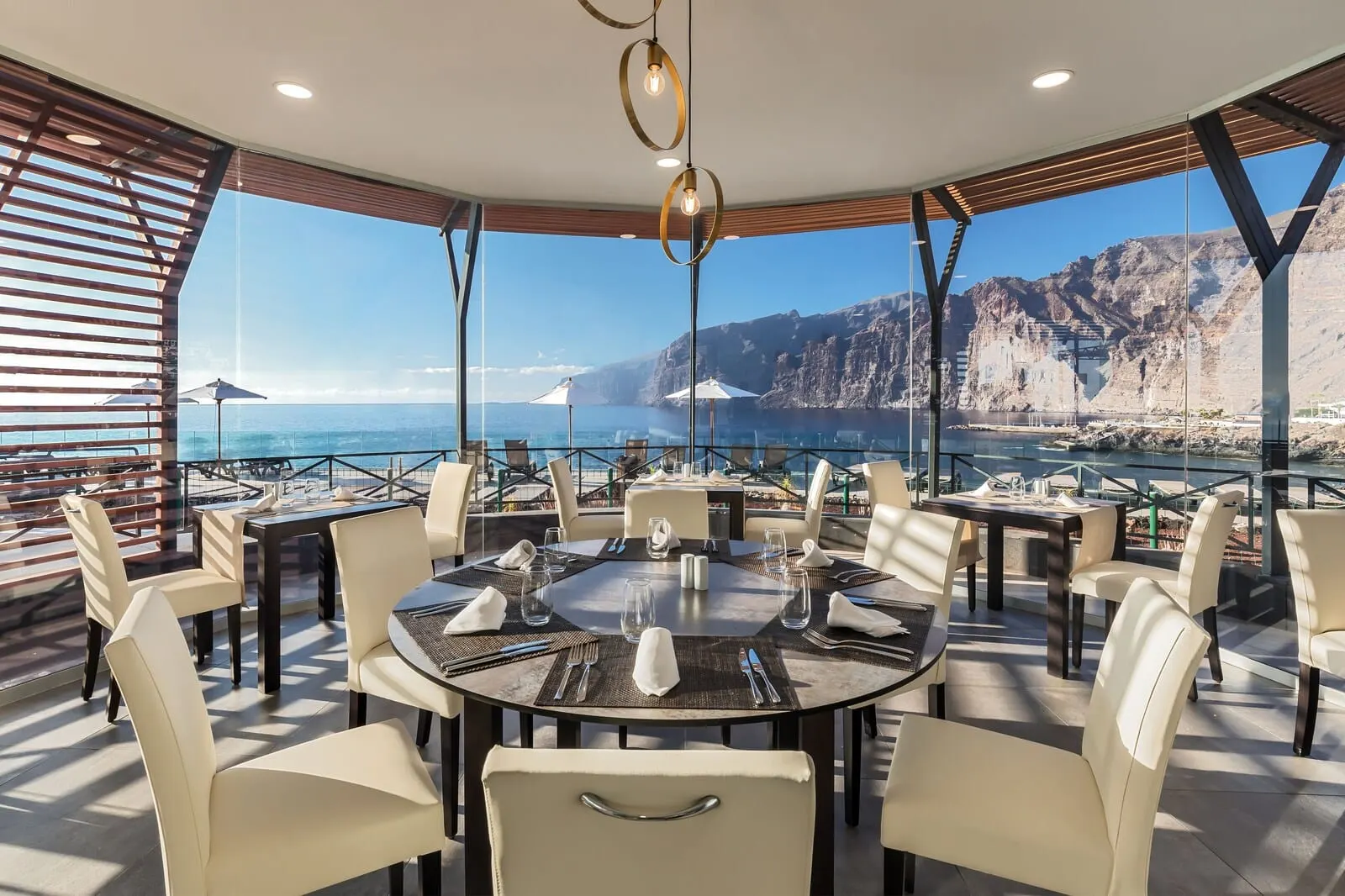 Barceló Santiago: A dining area with round tables, white chairs, and a view of the sea and cliffs