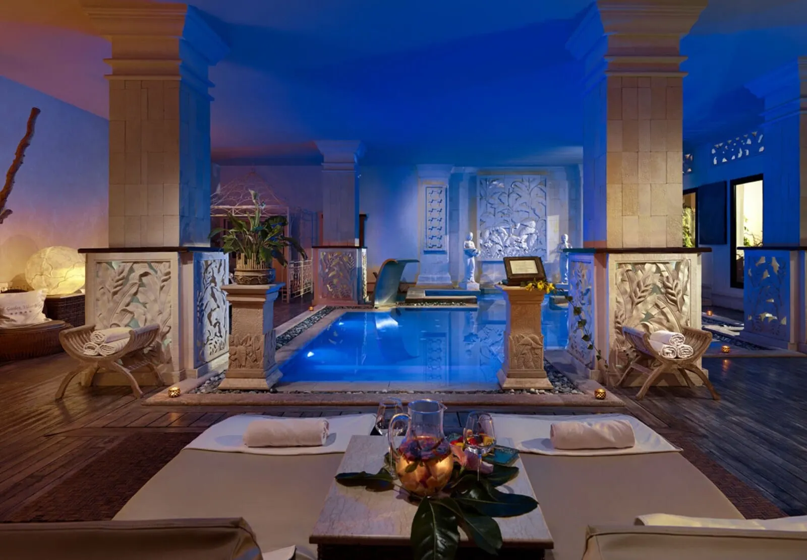 Royal Garden Villas & Spa: A luxurious spa area with a pool, seating, and a table with a pitcher of fruit