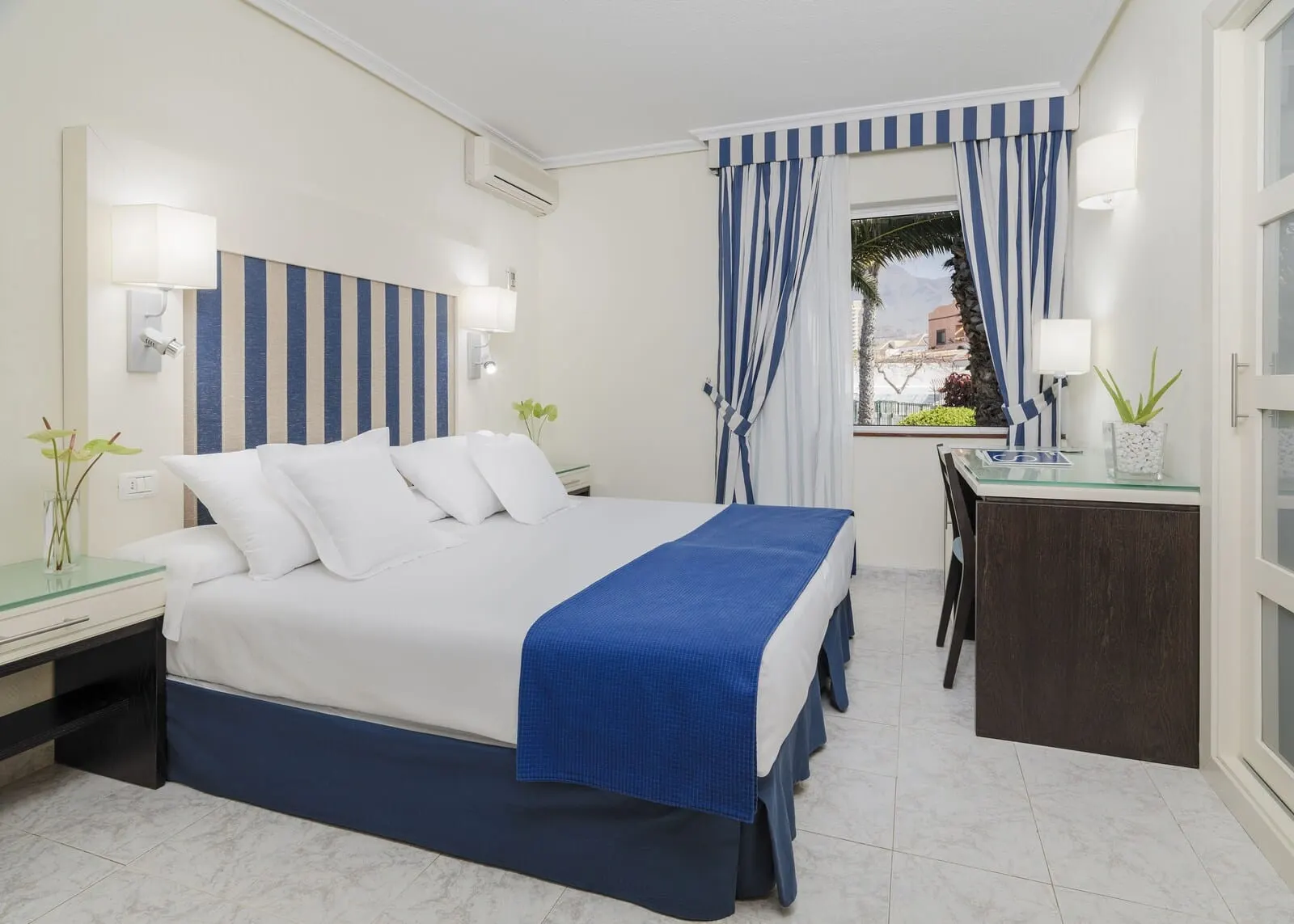 H10 Las Palmeras: A bedroom with a bed, bedside tables, a desk, and a window with curtains