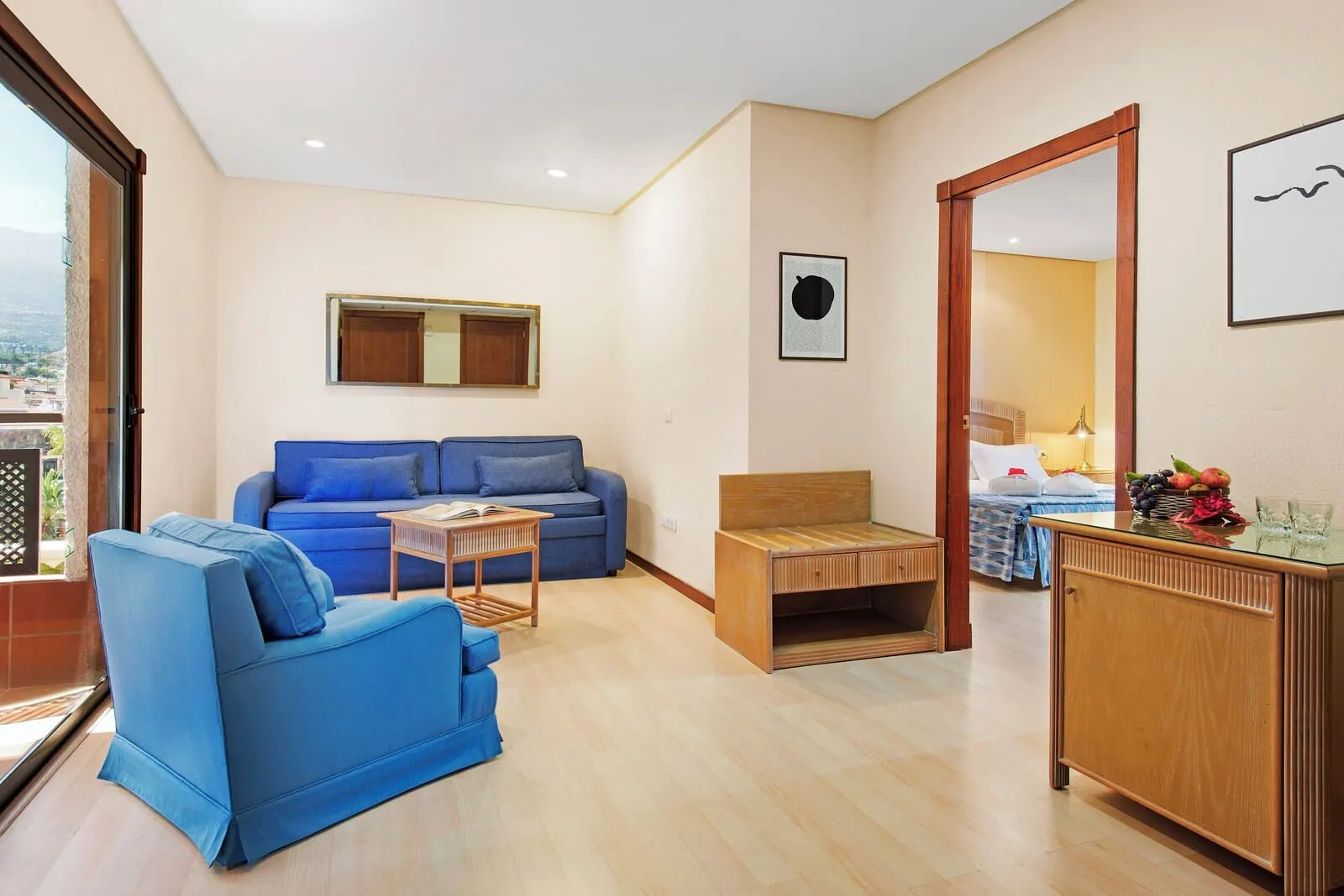 FERGUS Puerto de la Cruz: A modern living room with a blue sofa, a small wooden table, and a cabinet