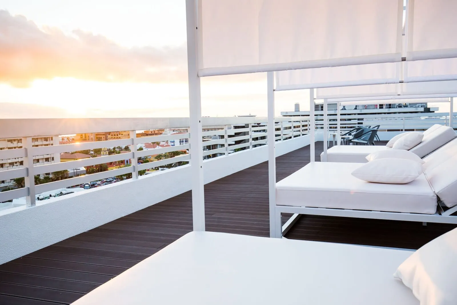 Coral Suites & Spa: A rooftop lounge with a white outdoor seating area, a view of the cityscape
