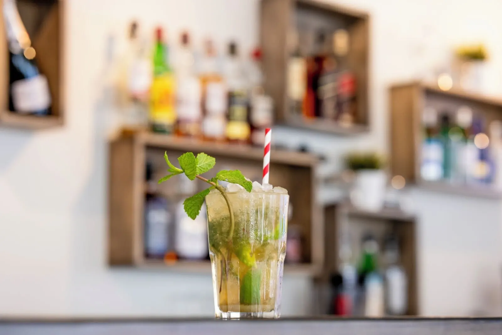 Ona El Marqués: A bar setting with a glass of drink, ice, mint, and a straw