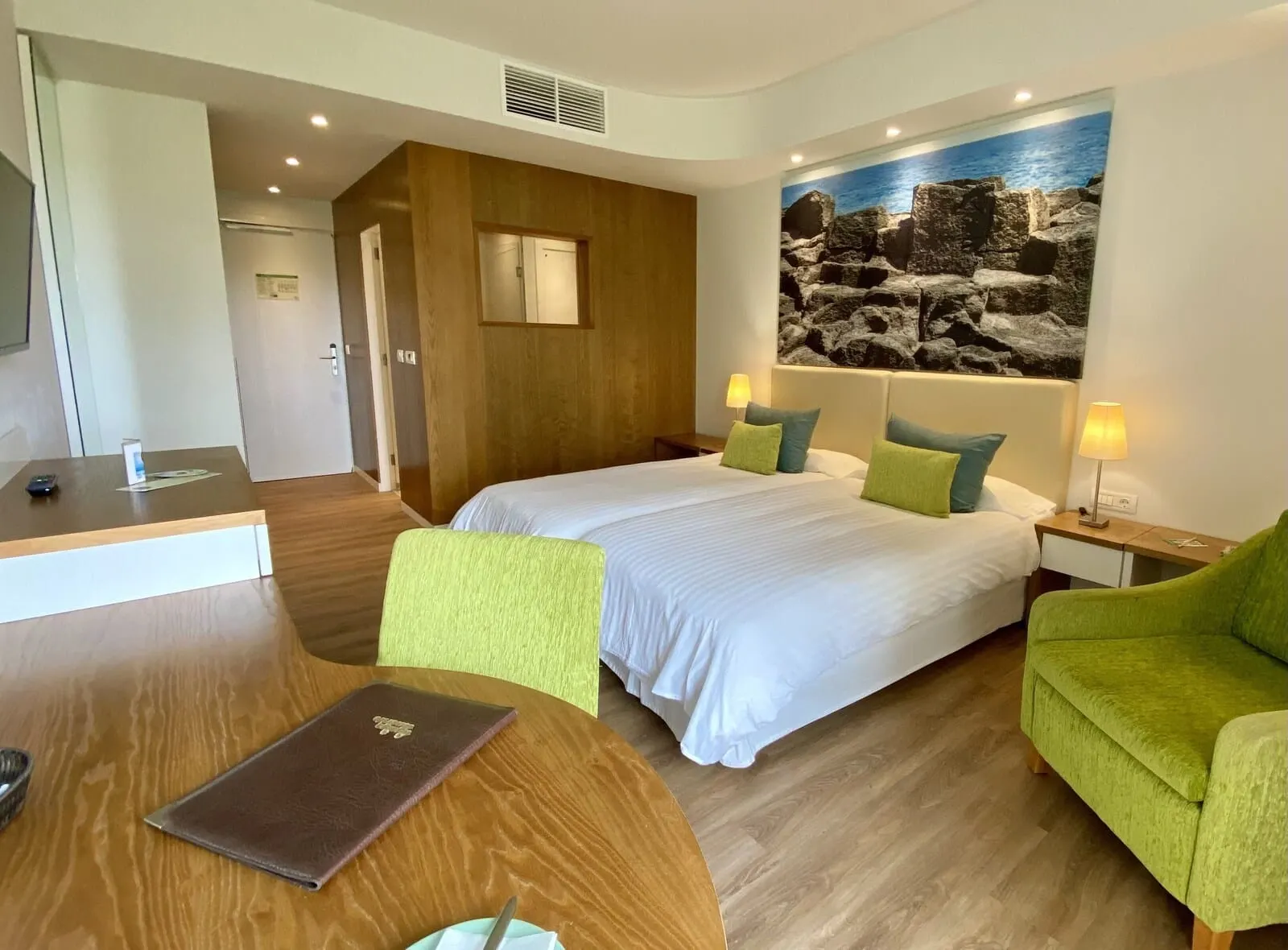 Hotel Tigaiga: A hotel room with a large bed, two bedside tables with lamps, a green armchair