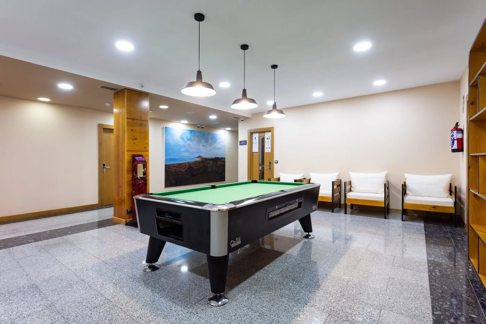 Hotel El Duque: A pool table in a room with a mural, a fire extinguisher, and a seating area