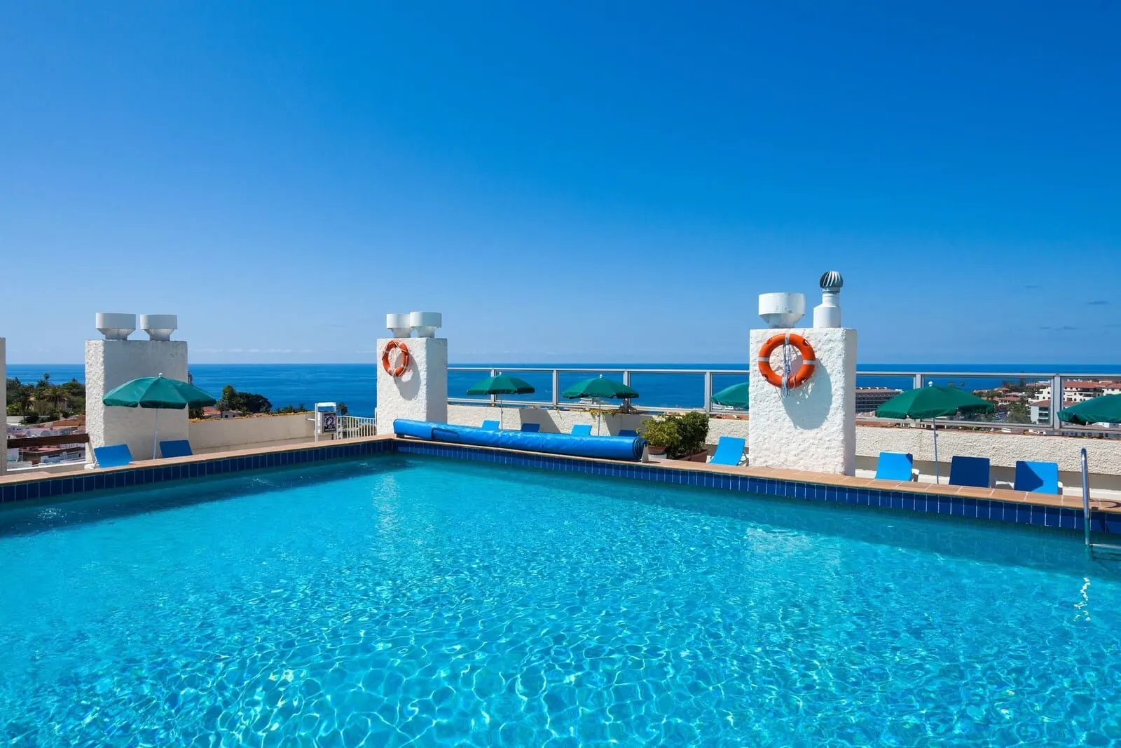Parque Vacacional Eden: A clear blue pool with lounge chairs and umbrellas, overlooking a beach