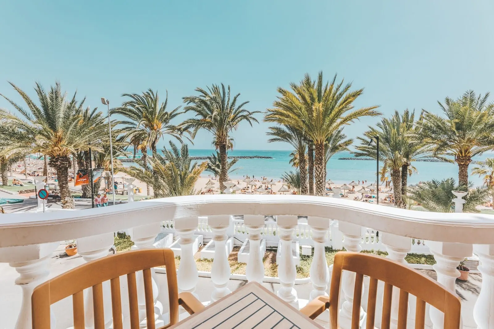 Cleopatra Palace: A balcony with a view of a beach, palm trees, and a clear sky
