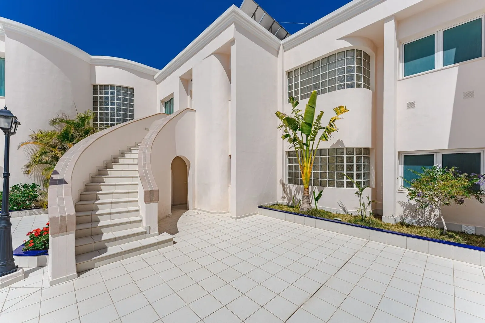 Flamingo Suites Boutique Hotel: A modern building with a curved staircase, large windows, and a tiled courtyard