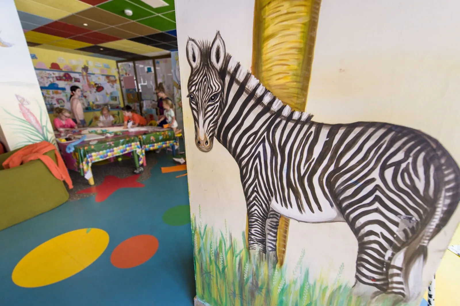 Ona Palm Beach: A zebra mural in a colorful room with a play area and tables