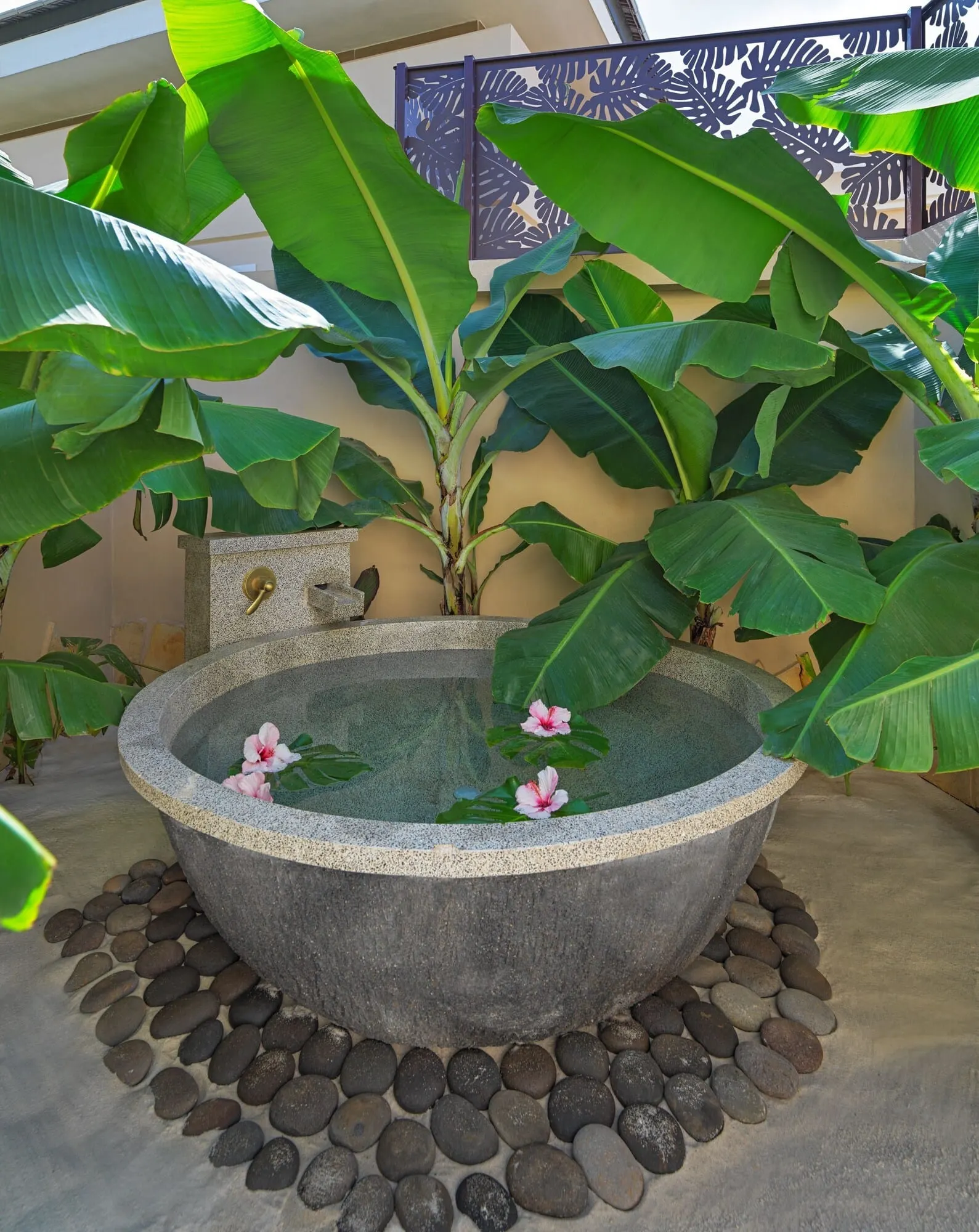 Royal River: A stone hot tub surrounded by rocks and large green leaves