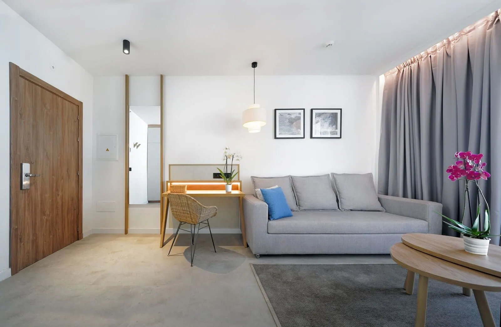 HOVIMA Suites Costa Adeje: A modern living room with a grey sofa, a wooden desk, a wicker chair