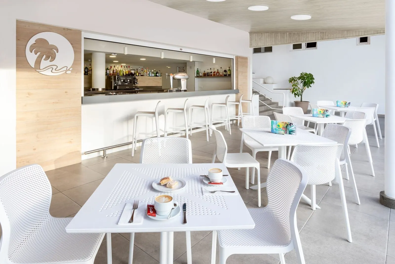 Hotel Tropical Park: A modern cafe with white furniture, a bar area