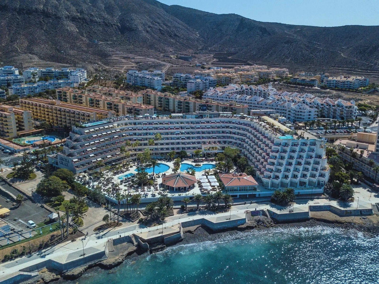 Arona Gran Hotel: A large resort with multiple swimming pools, a beachfront, and a mountainous backdrop