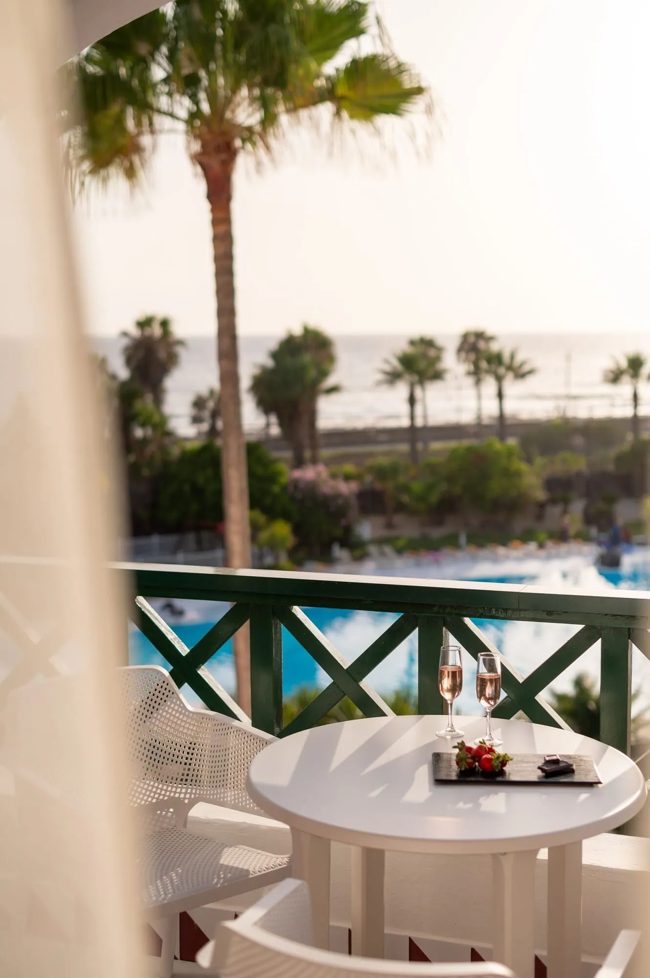 Parque Santiago IV: A balcony with a white table set for two, overlooking a pool and palm trees
