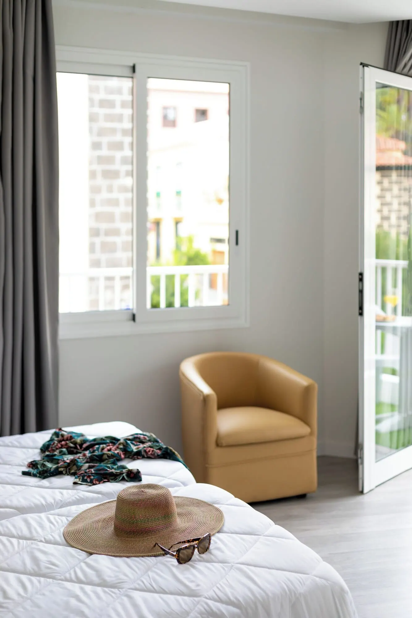 Hotel Boutique HC Maga: A bedroom with a bed, a chair, and a window with a view of a building