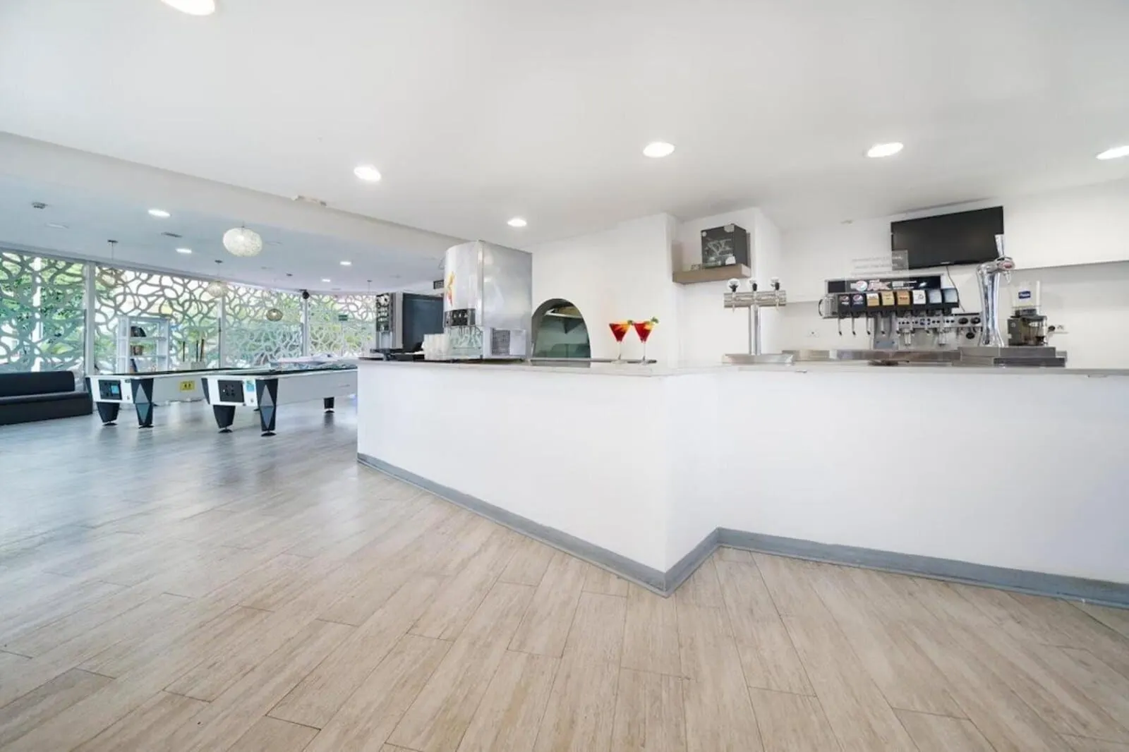 BLUESEA Bahía Fañabé Villas: A modern, spacious bar area with a high counter, a large screen, and a coffee machine